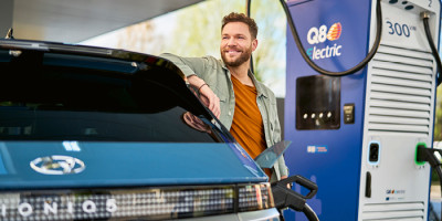 Q8 electric - Een man die aan het wachten is tot haar auto is opgeladen aan een laadpaal